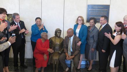 Assemblymember Reyes taking a picture with the statue and guests