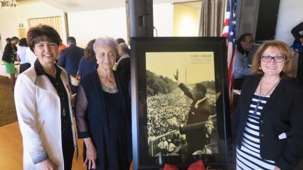 Assembly member Reyes and guest taking a picture next to a photo of Dr.King