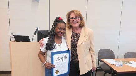 Assemblymember Reyes taking a picture with guest and her certficate 