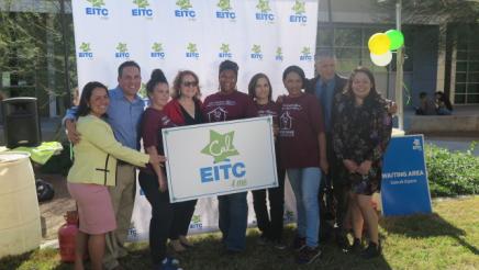 Assemblymember Reyes taking a group photo with Cal EITC 4 Me banner